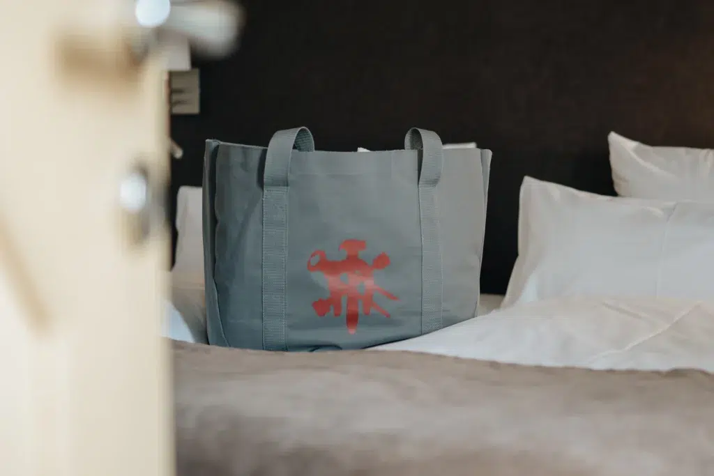 Graue Einkaufstasche mit rotem abstraktem Design, perfekt für Ihr Refugium in der Ferienwohnung Seefeld.