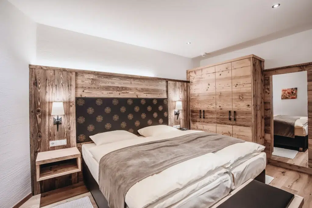 Modernes rustikales Schlafzimmer in der Ferienwohnung Seefeld mit Holzmöbeln, Doppelbett und warmer Beleuchtung.
