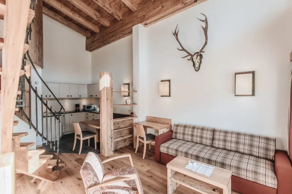 Gemütlich rustikale Ferienwohnung Seefeld Wohnzimmer mit kariertem Sofa, Holzmöbeln und Geweih.