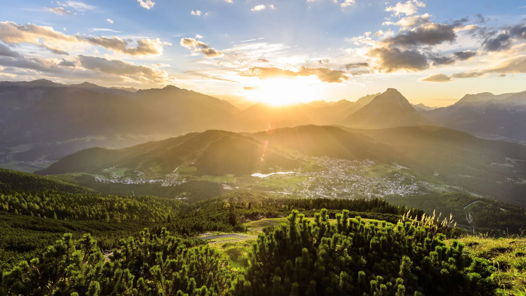 Sonnenuntergang über einem Bergtal, perfekt für alle, die nachhaltigen Urlaub machen möchten.