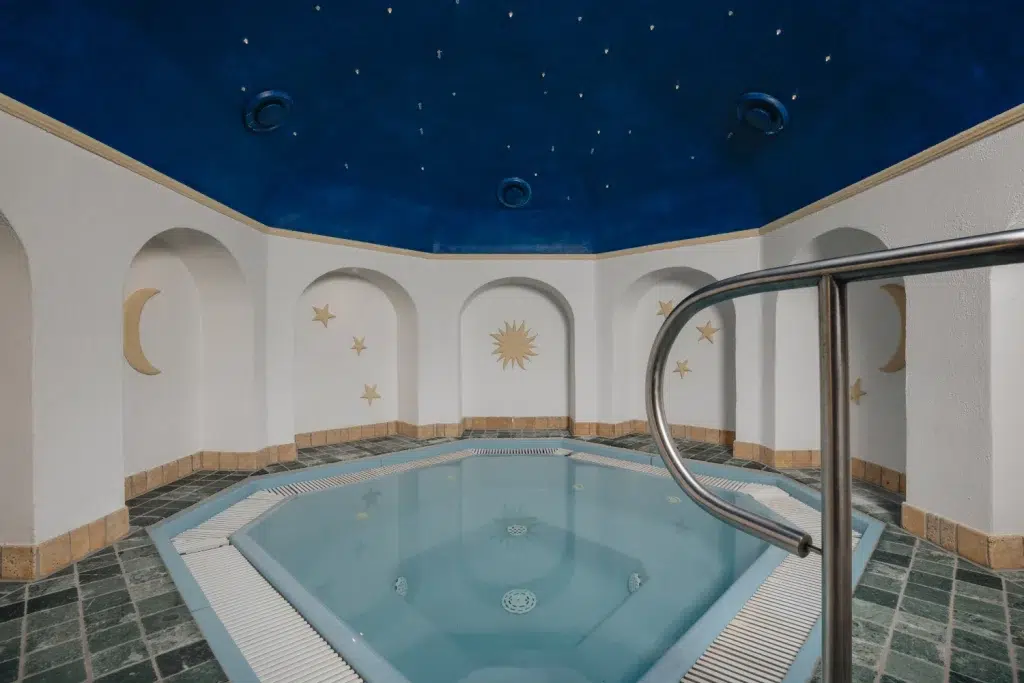 Innenwhirlpool mit Sternen- und Monddekor, blauer Decke, gefliesten Wänden im Wellness Seefeld.