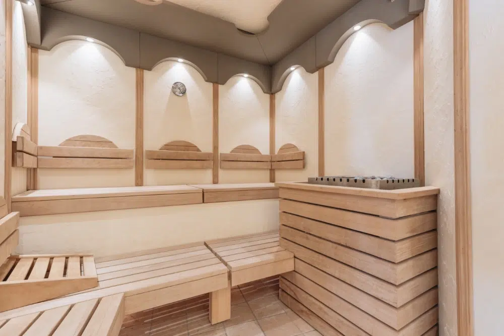 Moderner Saunaraum mit Holzbänken, Wänden und sanfter Wellness-Seefeld-Deckenbeleuchtung.