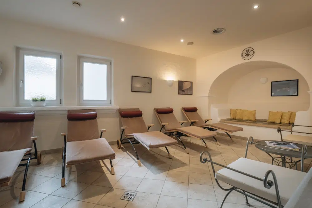 Eine entspannende Wellness-Seefeld-Lounge mit hellbraunen Liegen, gelben Kissen und sanfter Beleuchtung.