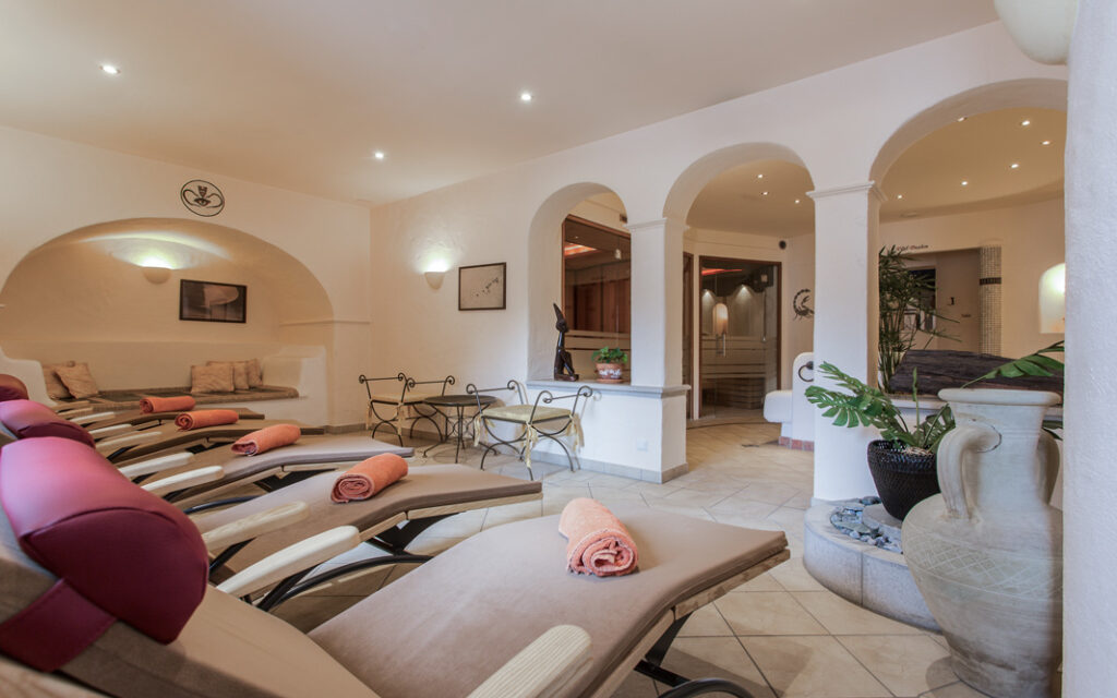Eine Wellness-Seefeld-Spa-Lounge mit Liegestühlen, gerollten Handtüchern, Bögen und sanfter Beleuchtung.