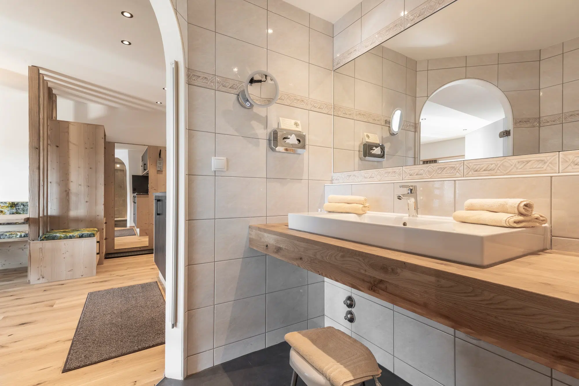 Modernes Badezimmer mit einem großen Spiegel, einem Waschbecken und gefalteten Handtüchern auf einer hölzernen Arbeitsplatte.